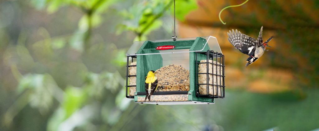 The platform feeders with bird on it and a bird flying around it.